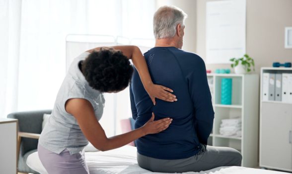 Physiotherapy, back pain and senior man with chiropractor for wellness, health and mobility. Health.