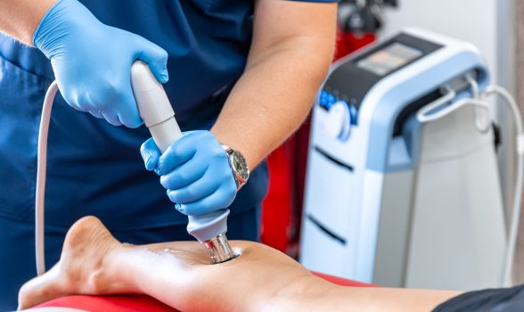Shock wave therapy, the magnetic field, rehabilitation, physiotherapist doctor performs surgery on a patient's shin.